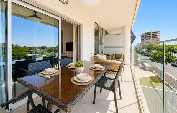 Natürliches Licht strömt durch breite Glastüren in diesen einladenden Wohnbereich und schafft eine harmonische Verbindung zur Terrasse im Freien. Bequeme Sitzgelegenheiten, warme Holzmöbel und tro..